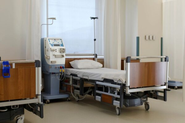 A hospital room with several Amsco/Steris 4080/5085 3pc Set Options beds and medical equipment.