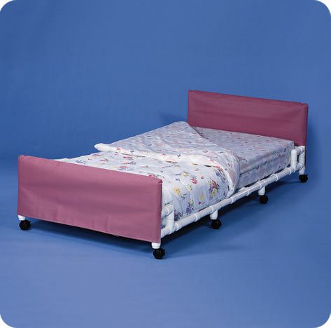A bed with pink sheets and white rails.
